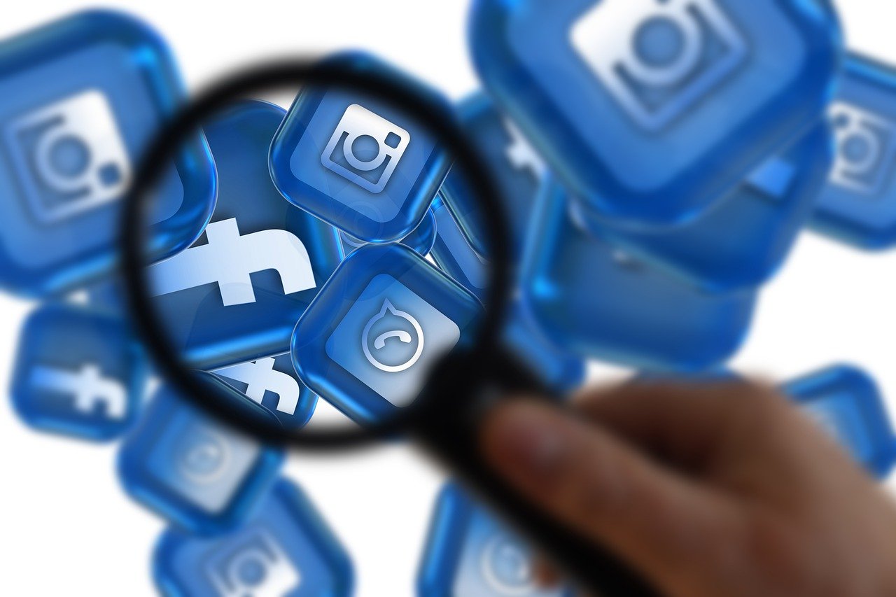 Imagem mostra uma mão segurando uma luta e, atrás, alguns quadrados de cor azul com os logotipos das empresas da Meta: Instagram e Facebook