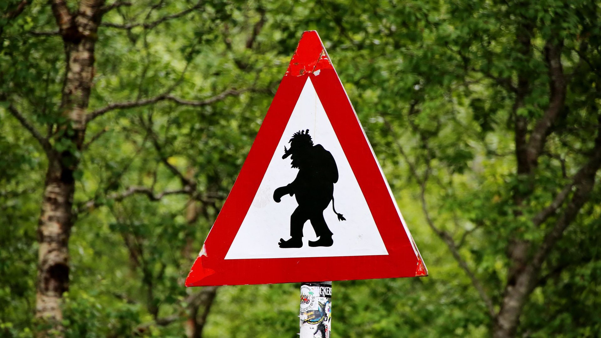 Placa mostra a silhueta de um troll, representando o troll da Internet; ao fundo há folhas de árvores