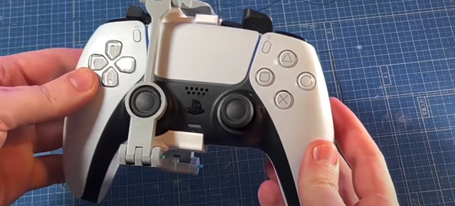 Mãos seguram controle DualSense do PS5 equipado com adaptador feito em impressora 3D