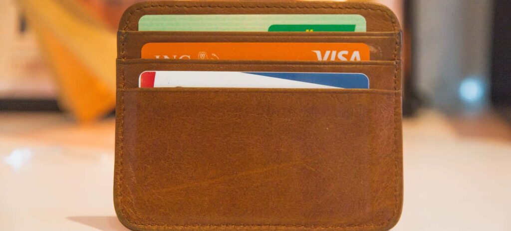 Imagem mostra uma carteira de couro aberta com três cartões de crédito encaixados nas divisórias