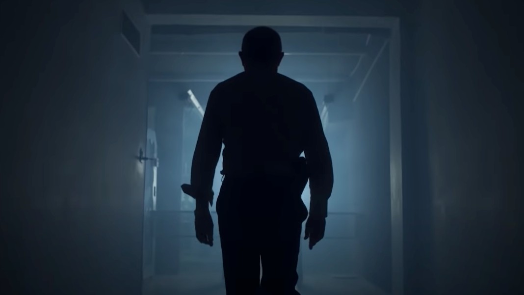 Imagem mostra a silhueta de um homem com uma arma na cintura, andando em direção a um corredor iluminado; cena do documentário 3 Tonelada$: Assalto ao Banco Central, da Netflix
