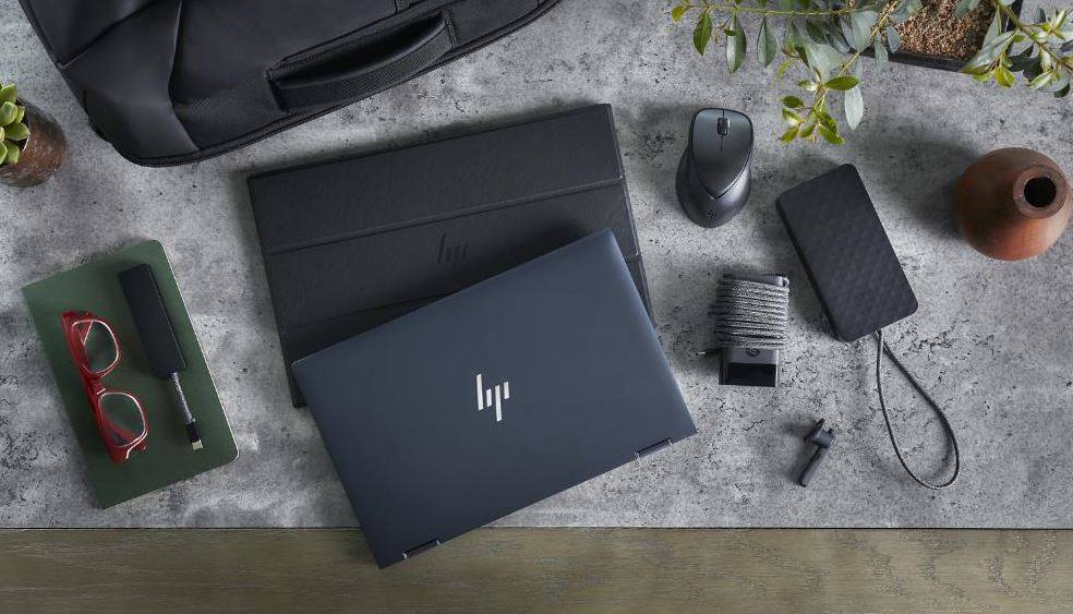 Imagem mostra o notebook HP Elite Dragonfly em cima de uma mesa, rodeado por acessórios como mouse, capa, óculos, smartphone, entre outros