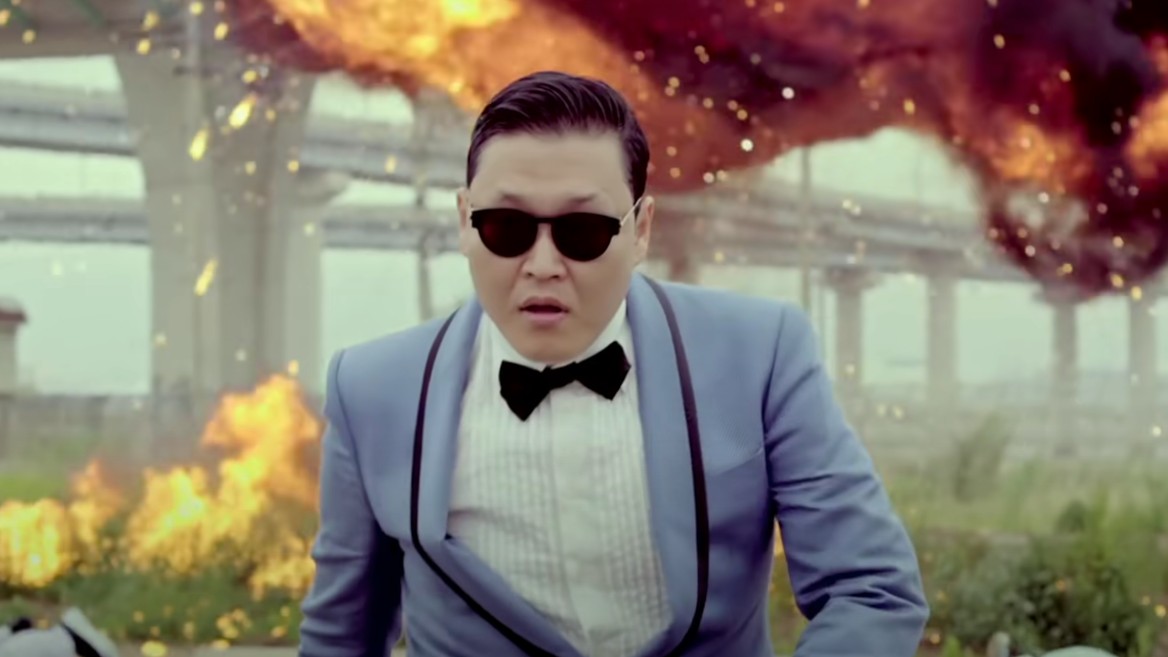 Captura de tela de um dos momentos do clipe musical Gangnam Style, do cantor sul-coreano PSY: é ele quem aparece na imagem, de óculos escuros e vestindo um terno azul