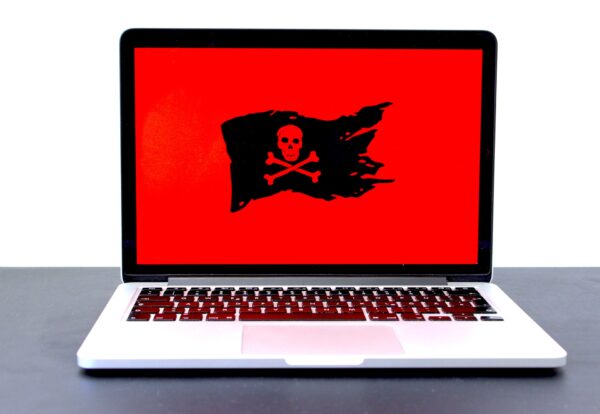 Ilustração de malware: uma bandeira virtual preta com uma caveira desenhada aparece em um fundo vermelho na tela de um notebook