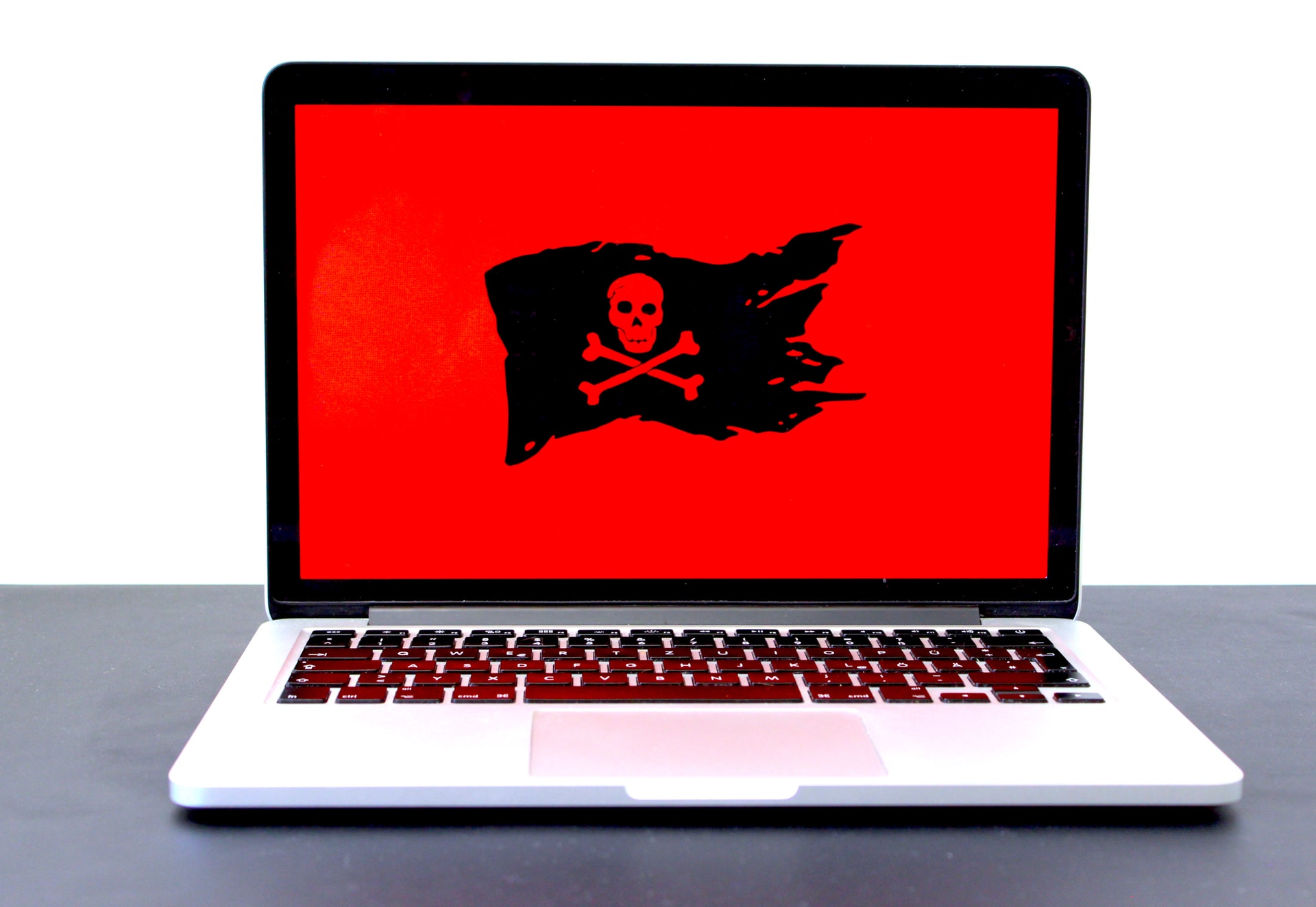 Ilustração de malware: uma bandeira virtual preta com uma caveira desenhada aparece em um fundo vermelho na tela de um notebook