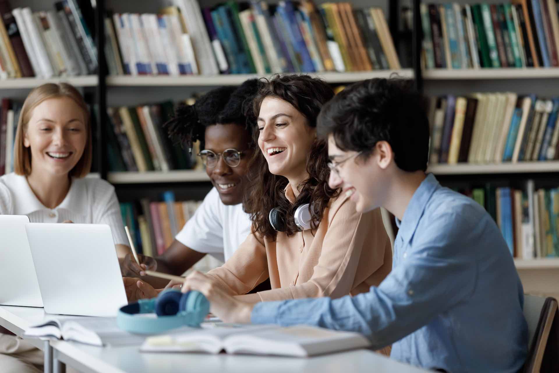 imagem mostra três jovens em frente a um computador, rindo; foto ilustra tecnologia