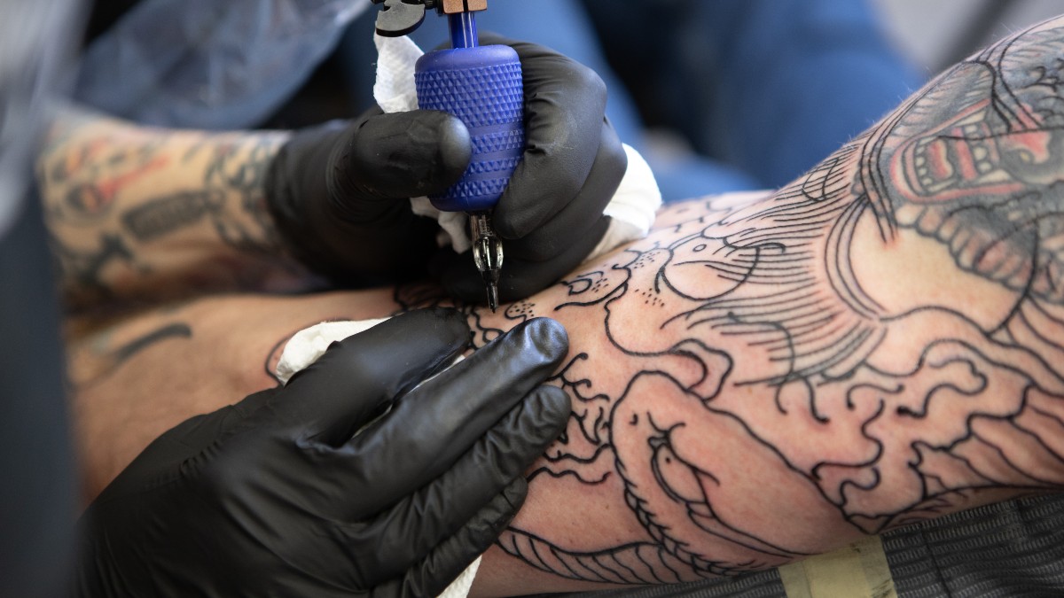 Imagem mostra um braço passando pelo processo de desenho de uma tatuagem