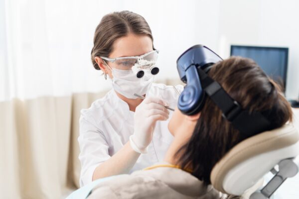 Imagem mostra uma dentista examinando um paciente enquanto ele usa um headset VR