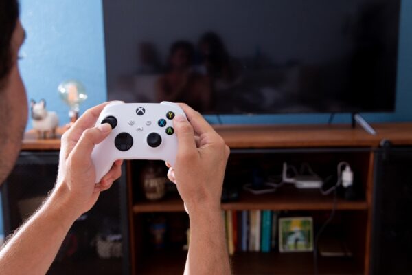 Imagem mostra um menino segurando um controle do Xbox One, em frente a uma TV. Imagem ilustra matéria sobre o mercado de jogos no Brasil