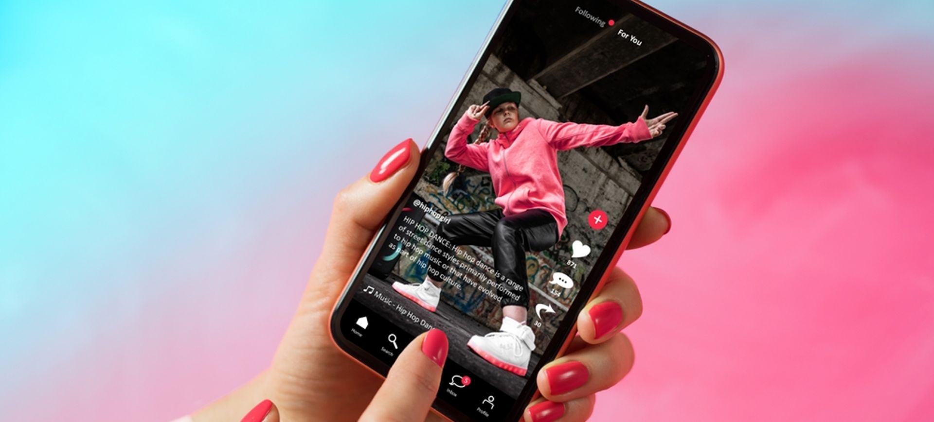 Mão feminina, com as unhas pintadas de rosa, segura um smartphone; na tela do aparelho é possível ver um vídeo de uma pessoa vestida com calças pretas, tênis e moletom rosa, representando criadores de conteíudo, também conhecidos como influenciadores digitais