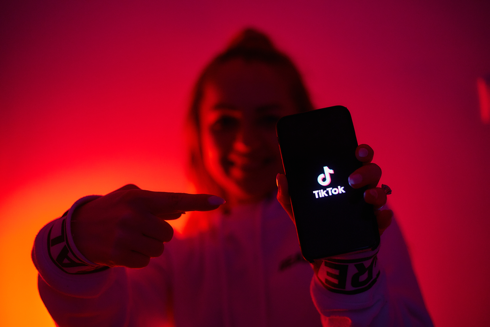 Imagem mostra uma mulher segurando um celular com o logotipo do TikTok em exibição na tela