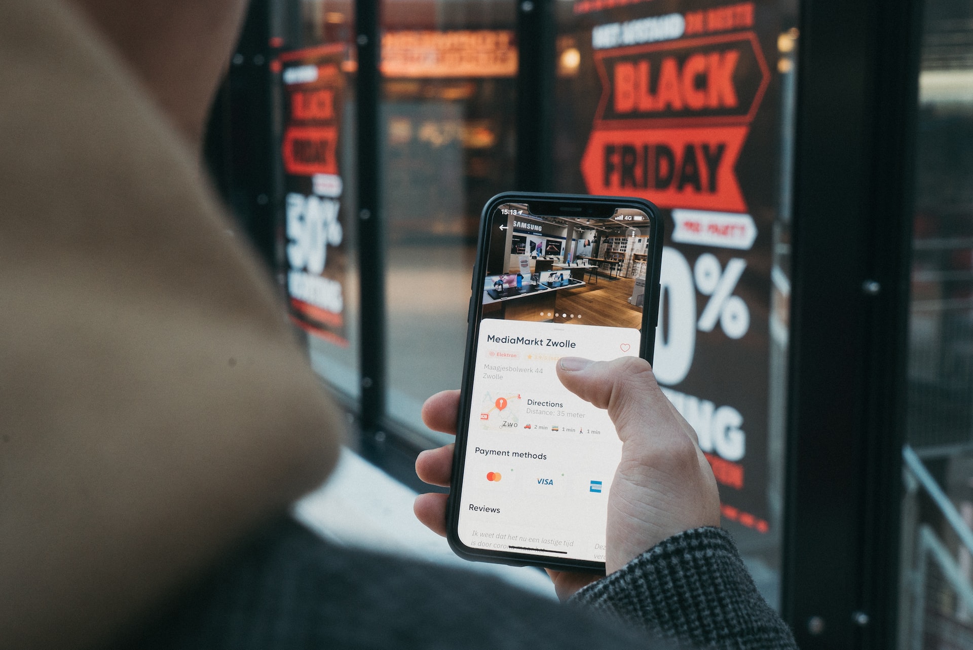 Imagem mostra homem usando o celular para escanear uma promoção de Black Friday em uma vitrine