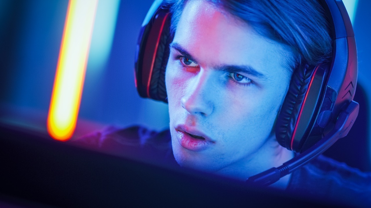 Imagem mostra um jovem jogando no PC e usado um headset