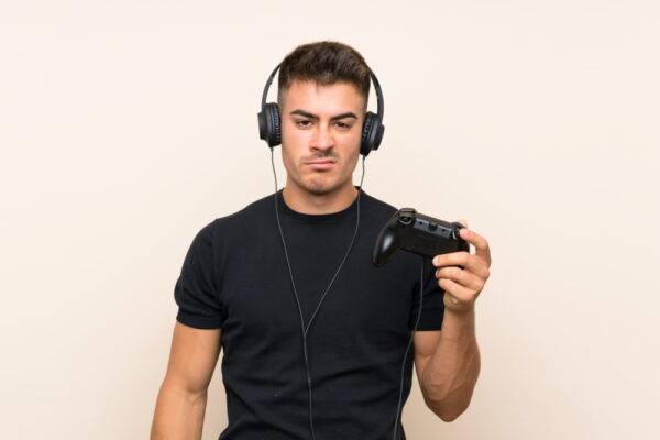 Imagem de um jovem com cara de bravo, usando headphones e controle de videogame