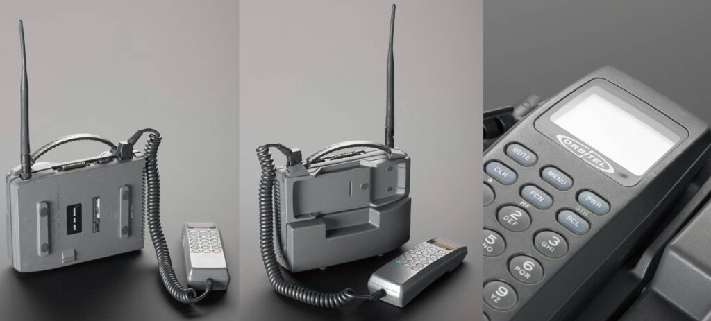 Três imagens que mostram diferentes ângulos (frente, costas e em detalhe) do telefone móvel Orbitel 901, de 1992