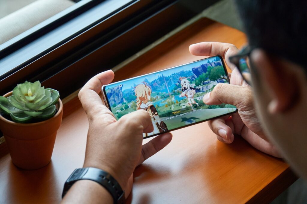 Imagem mostra um smartphone rodando Genshin Impact, líder do mercado de jogos mobile