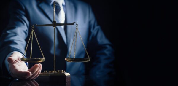 Imagem mostra uma mão segurando uma balança, simbolizando justiça e advocacia