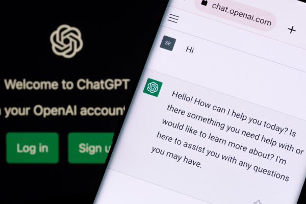 Imagem mostra tela do ChatGPT por trás de um celular com o logotipo do chatbot