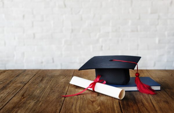 Imagem mostra um chapéu de universidade, com um diploma