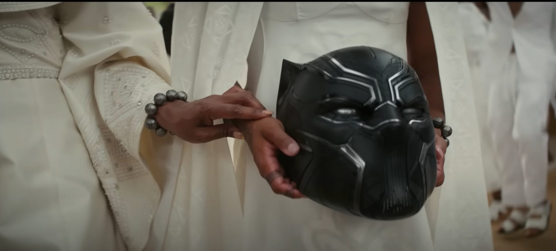 Mãos seguram o capacete do Pantera Negra, em uma cena do longa Pantera Negra: Wakanda Para Sempre