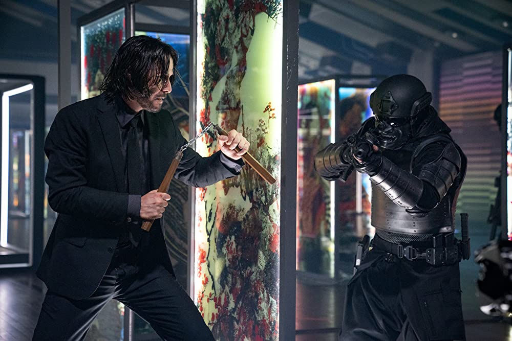 Imagem mostra cena do filme "John Wick 4: Baba Yaga", com Keanu Reeves lutando contra um inimigo armado com fuzil