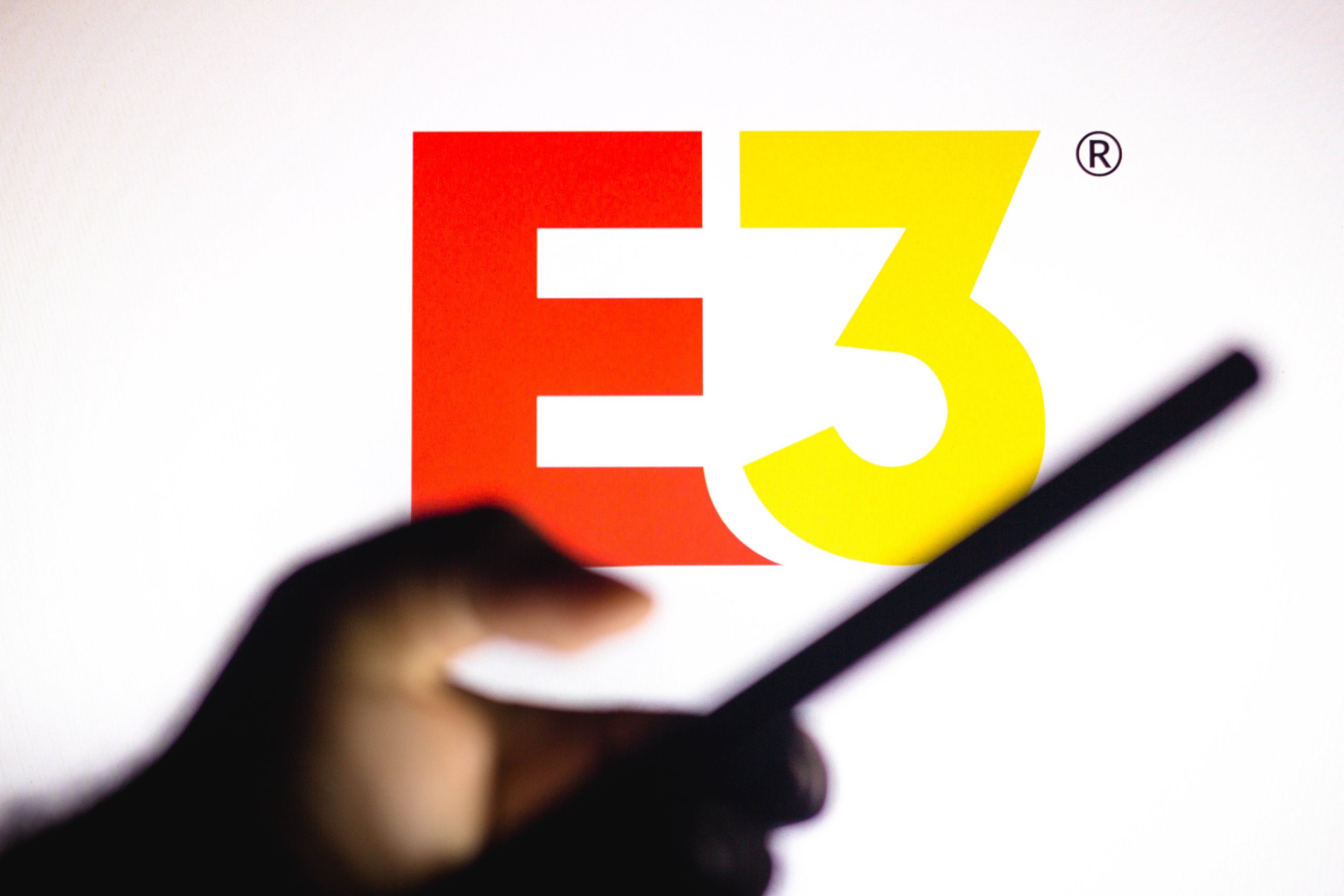 Imagem mostra o logotipo da E3 ao fundo, com um smartphone na frente