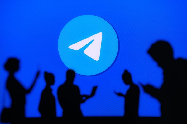 Imagem mostra o símbolo do Telegram com varias pessoas passando por baixo dele