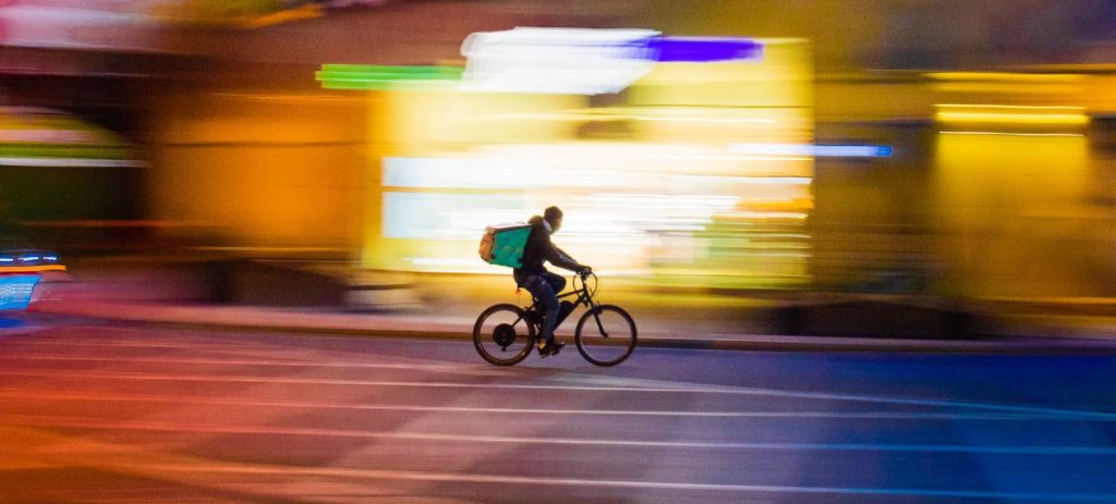 Na imagem, um entregador em uma bicicleta representa os motoristas e entregadores autônomos de aplicativos que serão beneficiados pelo grupo de trabalho estabelecido por novo decreto no Brasil