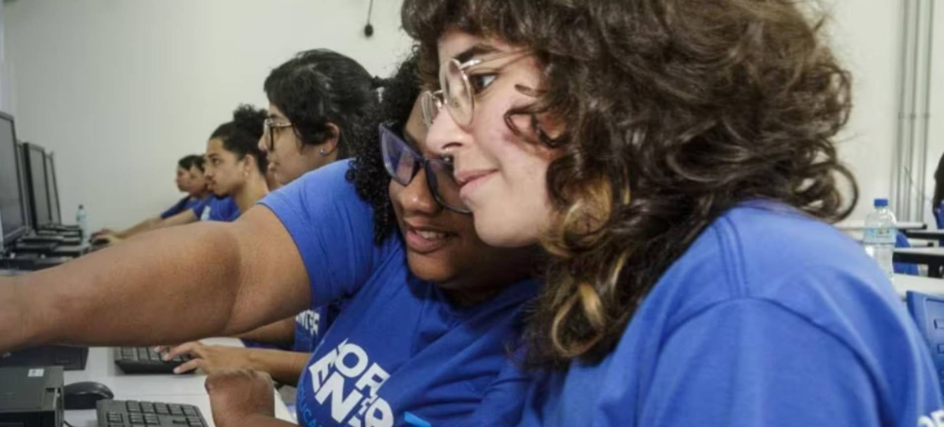 Duas jovens mulheres olham para tela de computadores; elas participam do programa Ford de capacitação em tecnologia