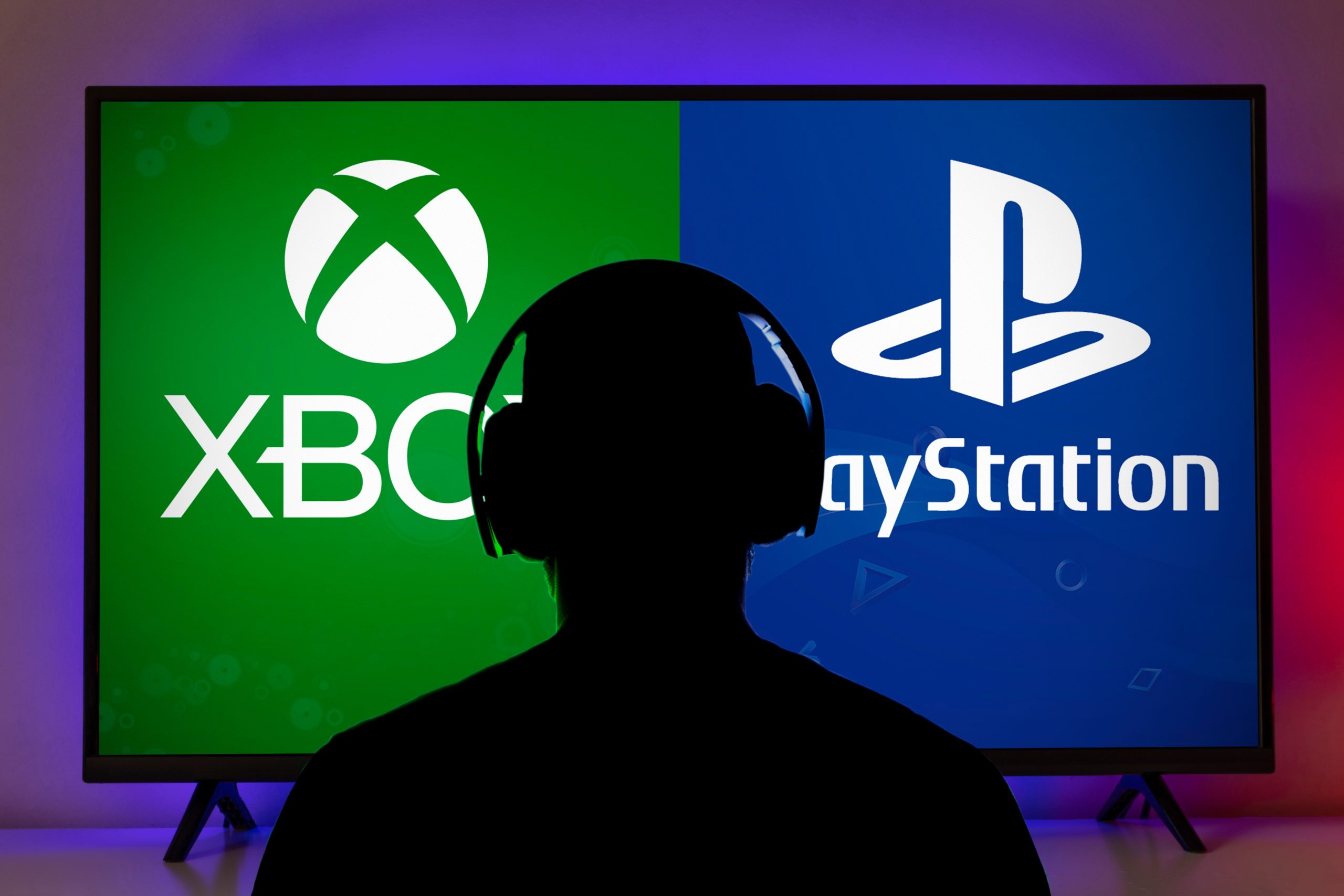 Imagem mostra a silhueta de um homem de costas, usando headphones, com uma televisão à sua frente dividida com os logotipos do Xbox e do PlayStation