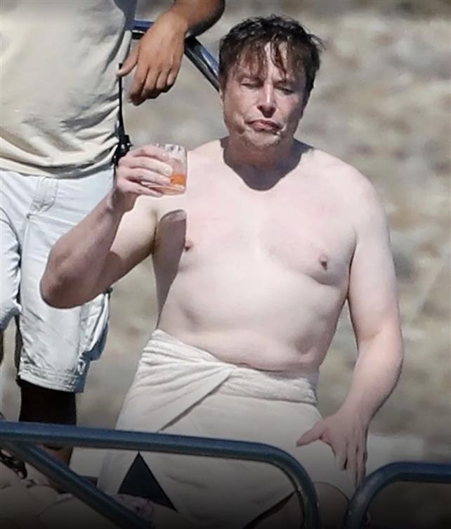 Foto mostra Elon Musk, CEO do Twitter, sem camisa em um barco, com bebida alcoólica em mãos