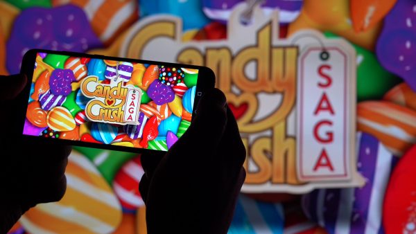 Imagem mostra um par de mãos segurando um celular com Candy Crush Saga na tela