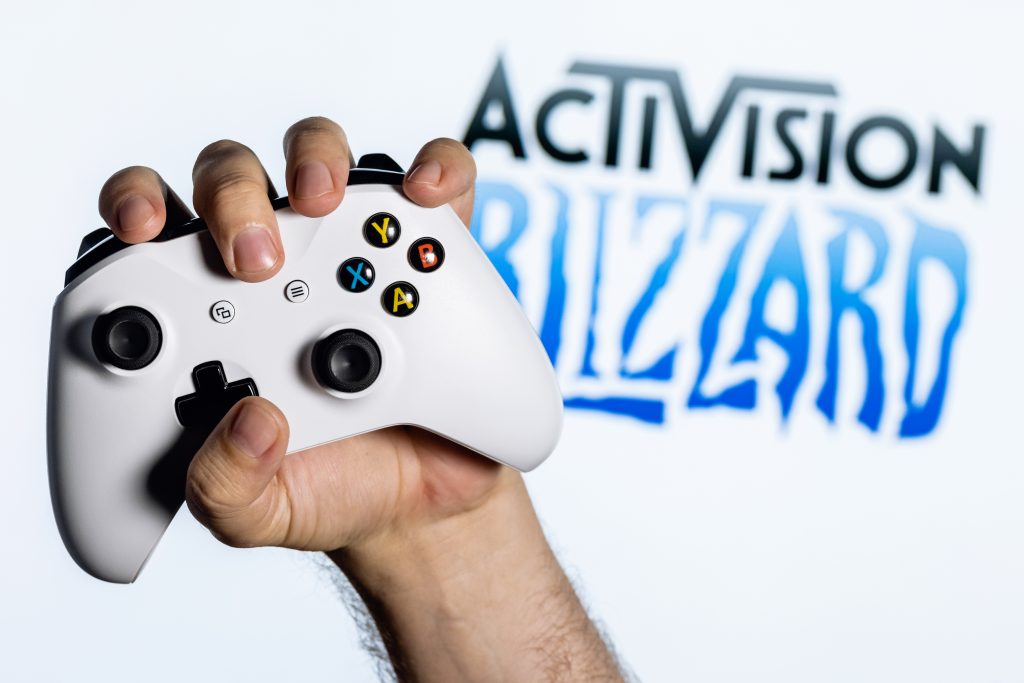 Imagem mostra logotipo da Activision Blizzard atrás de um controle do Xbox Series S