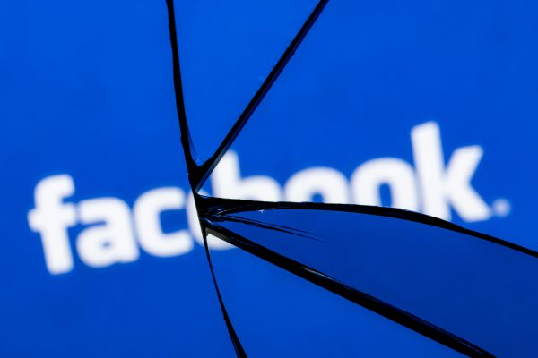 Imagem mostra o logotipo do Facebook, plataforma da Meta, quebrado como se por trás de um vidro