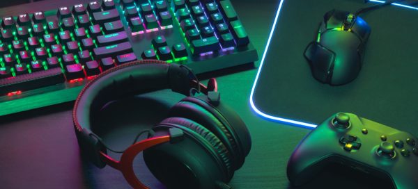 Imagem composta por um teclado RGB, fone de ouvido, controle de Xbox e mouse de PC para representar o mercado de desenvolvimento de games