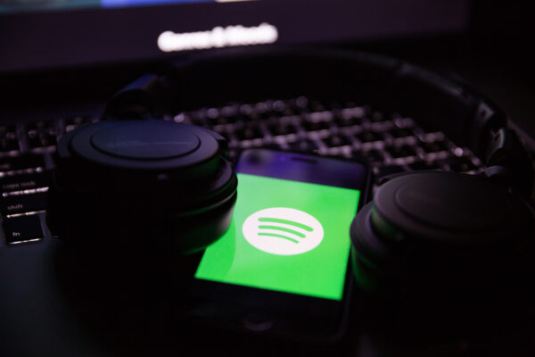 Imagem mostra o logotipo do Spotify em um smartphone, com um par de fones em volta