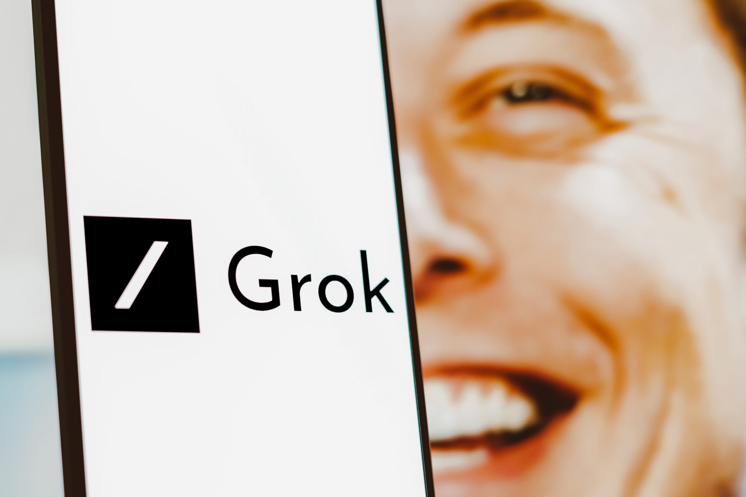 Imagem mostra o Grok, chatbot do X, à frente de um Elon Musk sorridente
