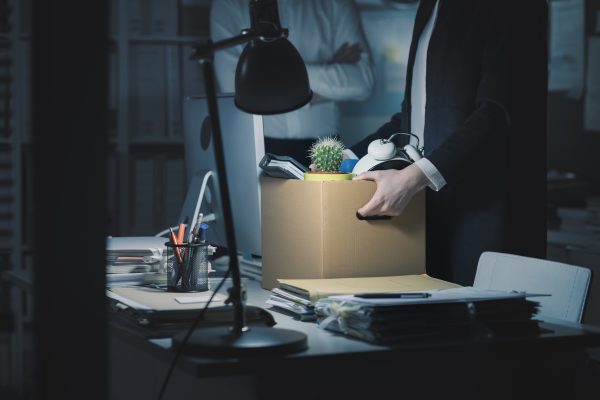 Imagem mostra um funcionário juntando seus bens em uma caixa, ilustrando situações de demissões