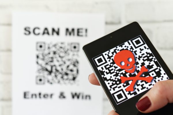 Imagem mostra um QR Code com um smartphone exibindo um símbolo de ameaça cibernética