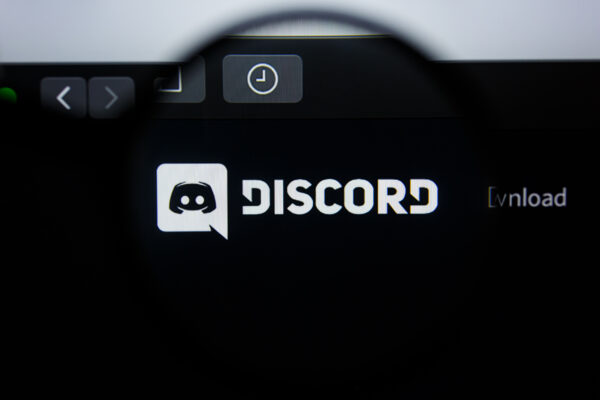 Imagem mostra o logotipo do Discord visto por uma lupa